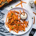 Carrot fries baked until crispy served on a plate with ranch dressing for dipping.