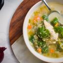Slow cooker chicken quinoa soup with kale, carrots, celery, and onions in a bowl with a spoon.