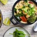 Coconut curry shrimp in a bowl with fresh vegetables, basil, green onions, and lime.