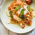 Creamy tomato mushroom and spinach pasta on a plate with whole grain pasta, creamy sauce, spinach, mushrooms, and parmesan cheese.