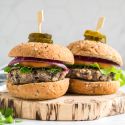 Double bean burgers made with black beans, white beans, cilantro, onion, and spices cooked and served on wheat buns with vegetables.