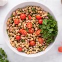 Easy bean salad with chickpeas, white beans, shallots, cherry tomatoes, and fresh herbs in a bowl.