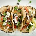Baked eggplant fajitas with peppers and onions in corn tortillas with queso fresco.
