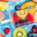 Fresh fruit popsicles made with kiwi, raspberries, peaches, cherries, blueberries, and coconut water.