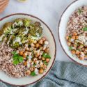 Garlic tahini broccoli bowls with cooked farro, roasted broccoli, roasted chickpeas, and tahini sauce in two bowls.