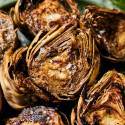 Grilled artichokes with flaky sea salt served on a plate with garlic butter.