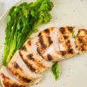 Grilled basil lime chicken breast with fresh basil, lime juice, lime zest, and broccoli on the side.