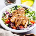 Grilled chicken Greek salad with black olives, feta cheese, tomatoes, Romaine lettuce, and red onions in homemade dressing.