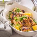 Grilled lemon dijon chicken thighs with fresh lemon and parsley in a white dish with a linen napkin.