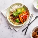 Ground beef bulgogi bowls with Korean flavored beef, cucumbers, carrots, red peppers, cabbage, and rice in a bowl. 