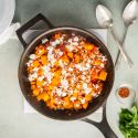 Ground turkey and butternut squash skillet with tomatoes and fresh herbs in a ceramic baking dish.