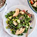 Honey lime kale and quinoa salad with sliced apples, dried cranberries, and pumpkin seeds in a bowl with cooked quinoa on the side.