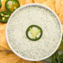 Jalapeno ranch dressing with Greek yogurt, herbs and jalapenos in a small dish with chips on the side.