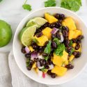 Mango salsa with fresh mango, black bans, red onion, cilantro, and lime juice in a bowl.