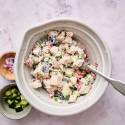 Mediterranean chicken salad with cucumbers, roasted red peppers, dill, parsley, and red onion in a bowl with lettuce on the side.