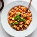 One pot chicken pasta with marinara sauce, chicken breast, melted cheese, and fresh basil in a bowl.