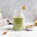 Peanut butter banana green smoothie served in a glass with a slice of banana and a straw.