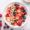 Peanut butter and jelly yogurt bowl with peanut butter, strawberry jelly, peanuts, and fresh fruit.