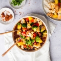Pineapple chicken stir fry with chicken breast, fresh pineapple, broccoli, cauliflower, and red bell peppers in a bowl with rice.