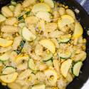 Gnocchi with zucchini and corn in cream sauce in a skillet.