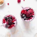 Protein packed banana berry smoothie with yogurt served in two glasses with berries on top.
