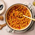 A pot of flavorful chickpea stew with tomatoes and spices sits on a table.