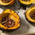 Roasted acorn squash with butter, brown sugar, and cinnamon on a baking sheet.