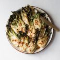 Roasted bok choy with soy sauce, garlic, ginger, and sesame seeds on a plate with a gold fork.