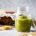 Roasted salsa verde with tomatillos, jalapenos, and cilantro in a mason jar with chips on the side.