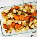 Roasted carrots and turnips with herbs in a glass container.