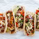 Roasted vegetable fajitas with bell peppers, onions, corn, carrots, zucchini, and pinto beans in tortillas with cheese and limes.