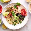 Rotisserie chicken taco bowl with black beans, bell peppers, onions, guacamole, and tomatoes.