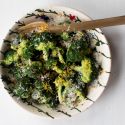 Sauteed broccoli with Parmesan cheese, lemon zest, red pepper flakes, and olive oil in a ceramic bowl with a wooden spoon.