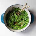 Sauteed snow peas with green onions, soy sauce, garlic, ginger, and sesame seeds with chopsticks.