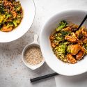 Sesame chicken with broccoli served in a bowl with sesame sauce and sesame seeds.