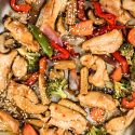Sheet pan Asian chicken stir fry with chicken breast, peppers, broccoli, and other veggies on a sheet pan.