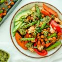 Sheet pan pesto chickpeas and vegetables on a plate with asparagus, sweet potatoes, chickpeas, carrots, cauliflower, and peppers.