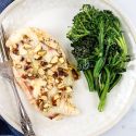 Chicken cordon bleu with ham and melted Swiss cheese on a plate with broccoli.