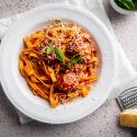 Slow cooker Italian meatballs served with pasta, parmesan cheese, and fresh basil.