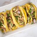 Slow cooker Banh Mi Pork with green onions, cucumbers, radishes, and cilantro in corn tortillas.