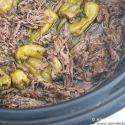 Slow cooker pepperoncini beef in a slow cooker with shredded beef and jarred pepperoncinis.