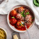 Slow cooker turkey meatballs in a shallow bowl with marinara sauce, fresh basil, and Parmesan cheese. 