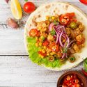 Spicy chicken tacos with corn in a tortilla with onions and sliced red jalapenos.