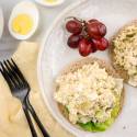 Tuna egg salad on a sandwich thin with red grapes and lettuce.