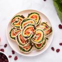Turkey pinwheels with cream cheese, dried cranberries, cheddar cheese, lettuce, and tomatoes wrapped in a tortilla and sliced into pinwheels.
