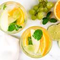 Vinho Verde white sangria with grapes, green apples, and orange in two glasses with fruit on the side.