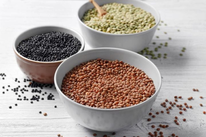 Three types of lentils including brown, black, and green in bowls.