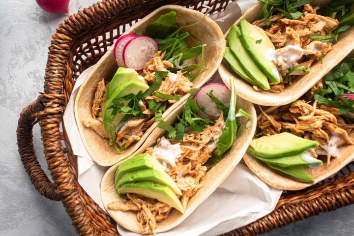 Healthy slow cooker chicken barbacoa tacos with avocado, cilantro, and radishes in corn tortillas.
