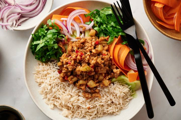 Asian ground turkey bowls with lean ground turkey, bell peppers, mushrooms, and water chestnuts served with rice, carrots, cucumbers, lettuce, and green onions.