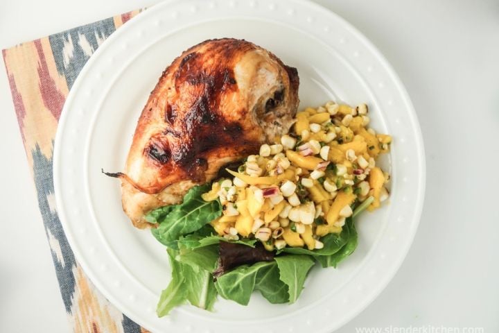 Baked chicken teriyaki with mango salad and greens on a plate.